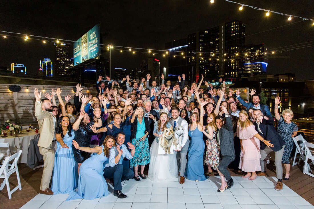 A large group of people are posing for a picture at a wedding reception.