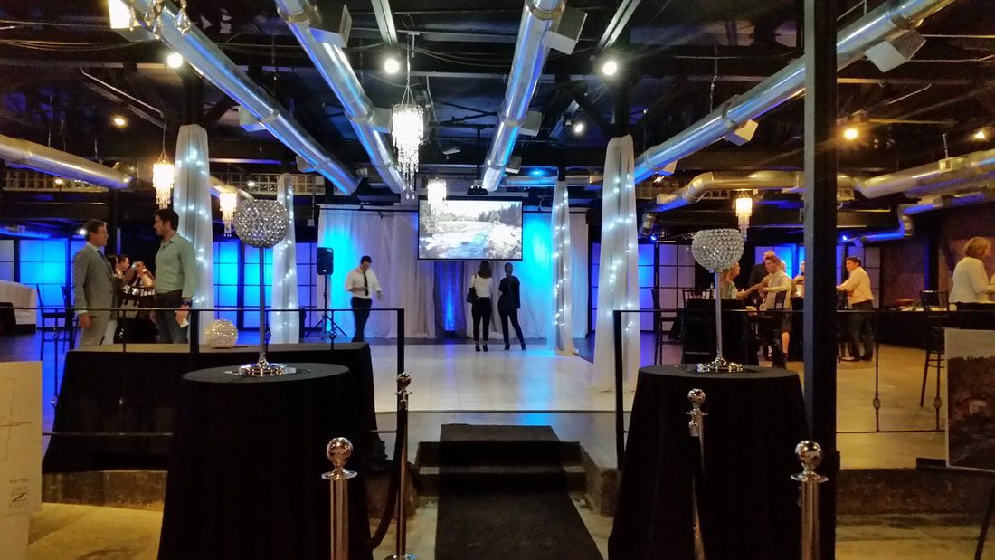 A large room with tables and a stage in the middle of it.