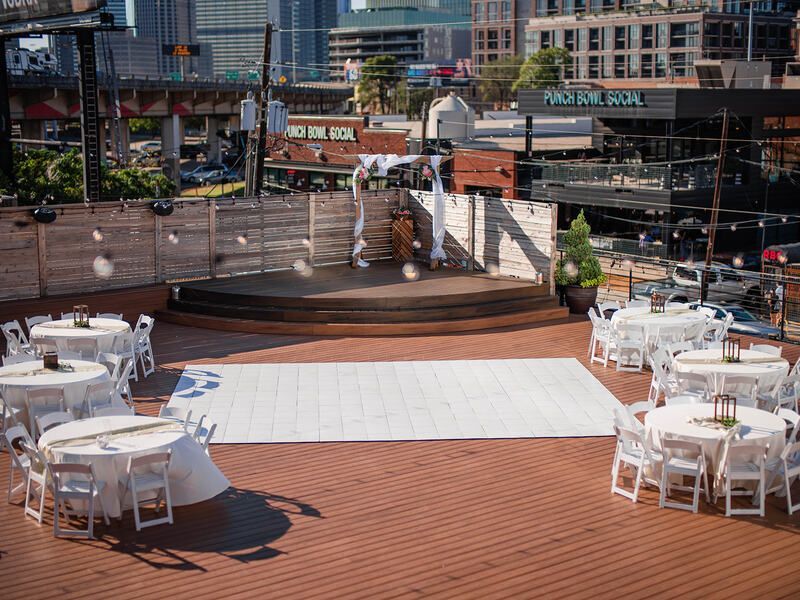 A large white dance floor is surrounded by tables and chairs.