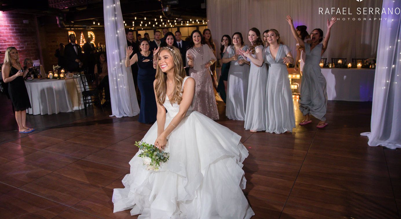 A bride in a wedding dress is throwing her bouquet to her bridesmaids.