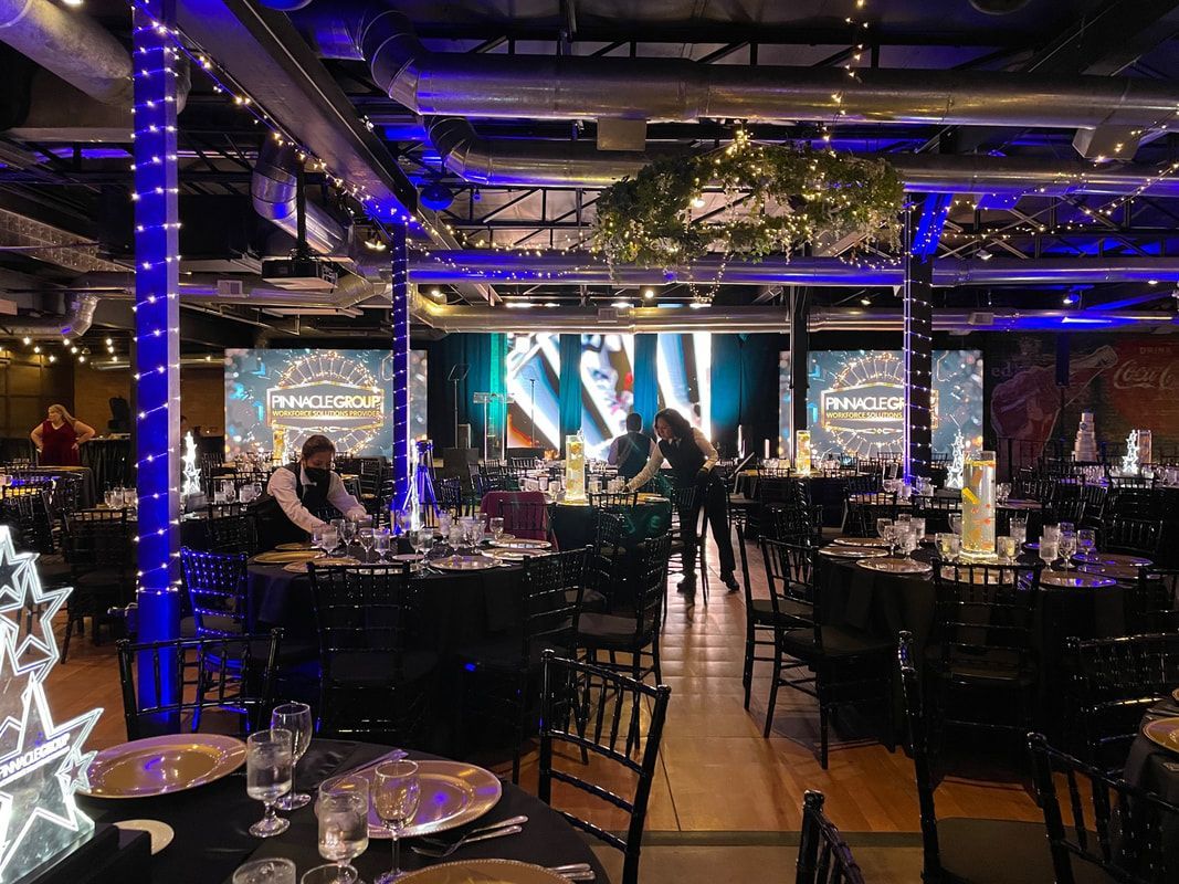 A large room filled with tables and chairs and a large screen.