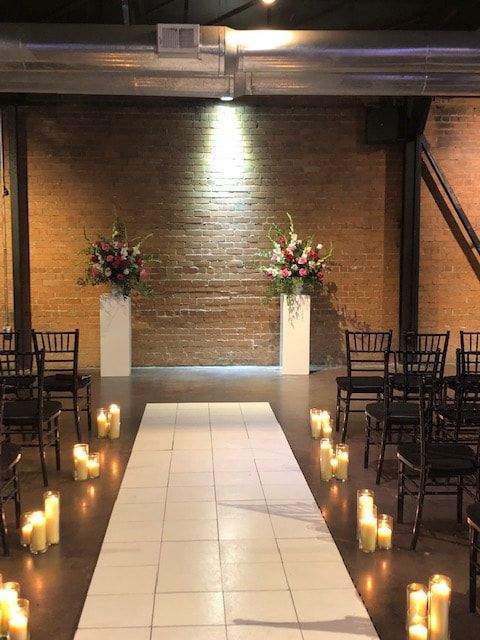 A wedding ceremony is taking place in a room with candles and flowers.
