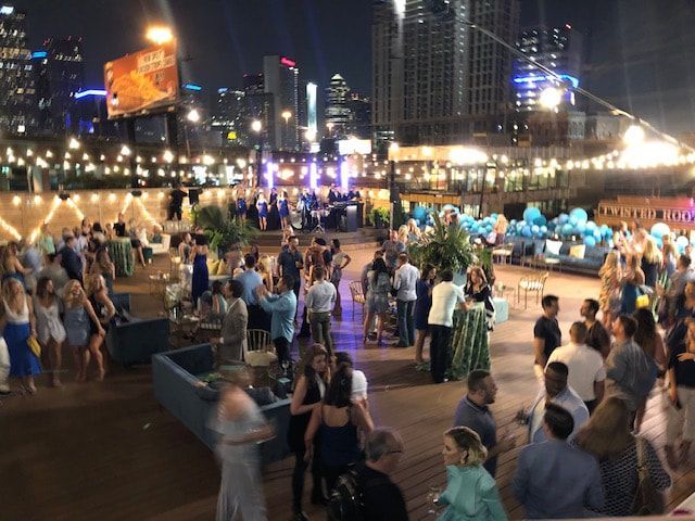 A large group of people are gathered on a rooftop at night.