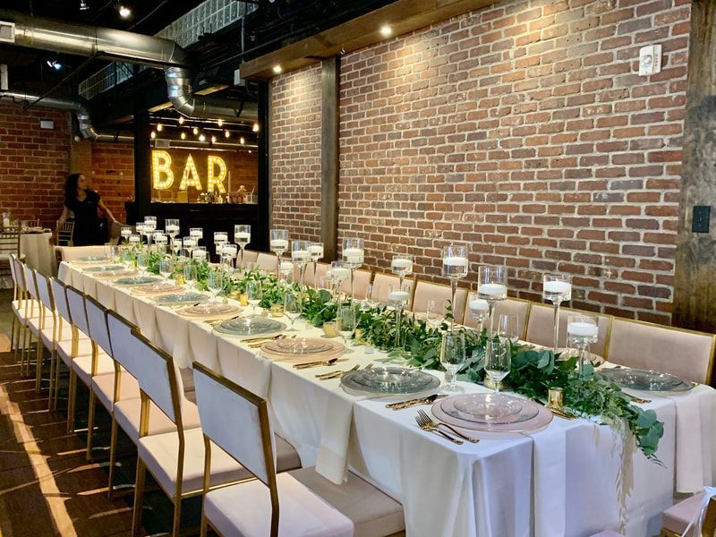 A long table with plates and candles in a room with a brick wall.