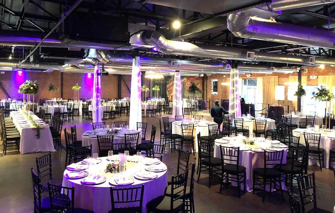A large room with tables and chairs set up for a wedding reception.