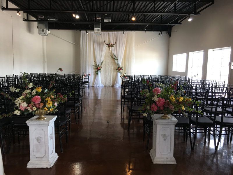 A large room filled with chairs and flowers for a wedding ceremony.