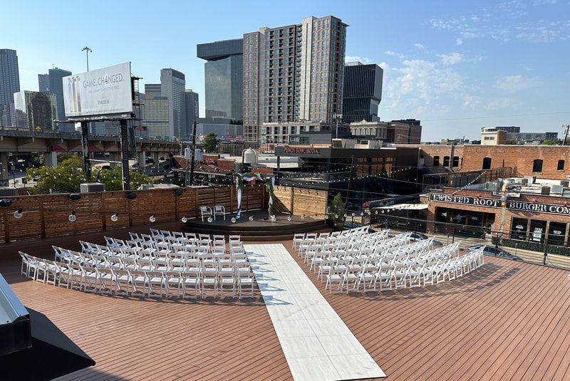 A wedding ceremony is taking place on a rooftop with a city skyline in the background.