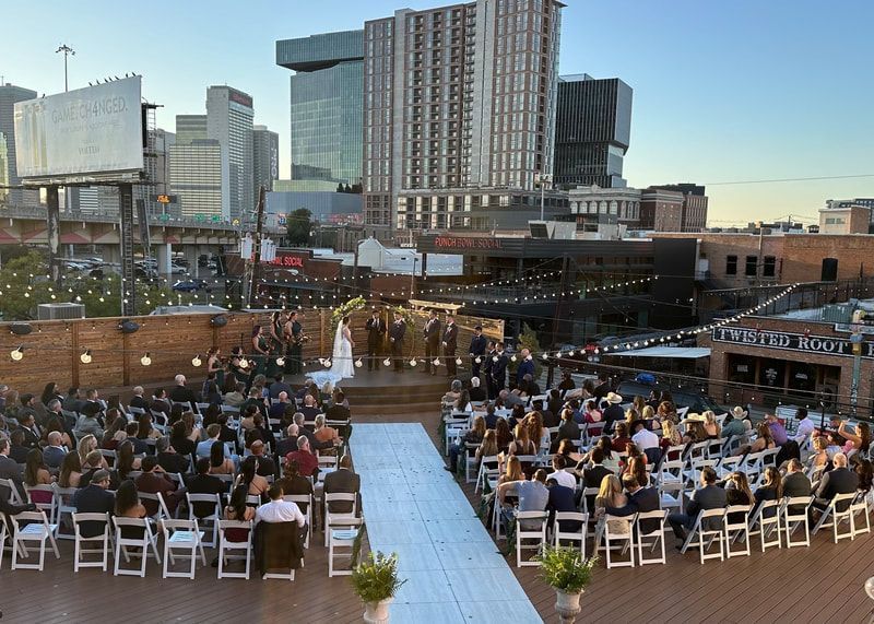 A large group of people are sitting at a wedding ceremony in front of a city skyline.