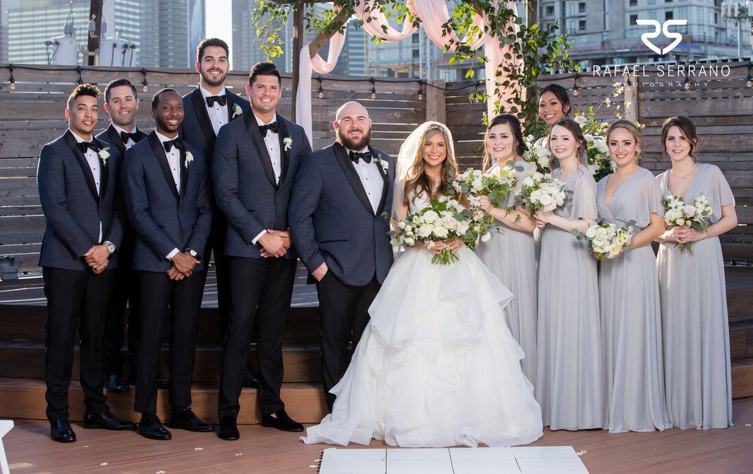 The bride and groom are posing for a picture with their wedding party.