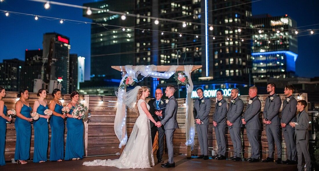 A bride and groom are getting married in front of their wedding party.