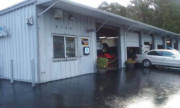Auto repair shop exterior with open garage bay, gray building, car. | Burrough & Sons Automotive Inc.