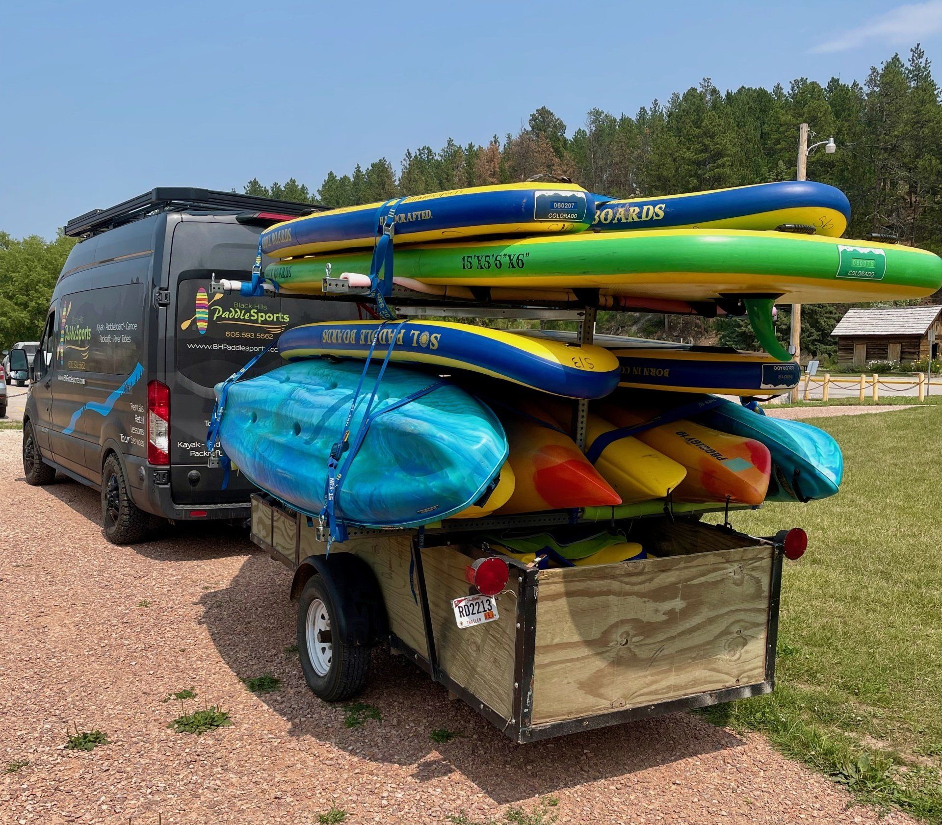 A van is parked next to a trailer full of kayaks