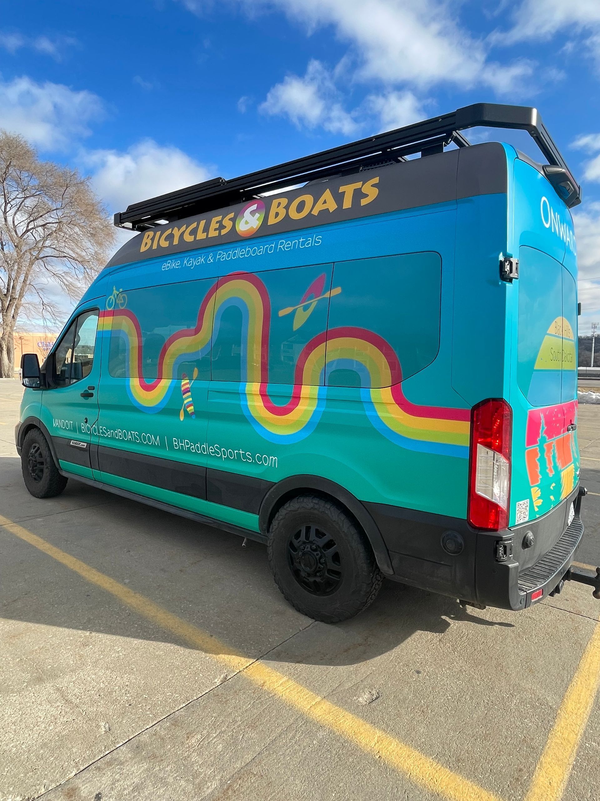 Colorful “Skis & Boats” van parked in a lot under a blue sky