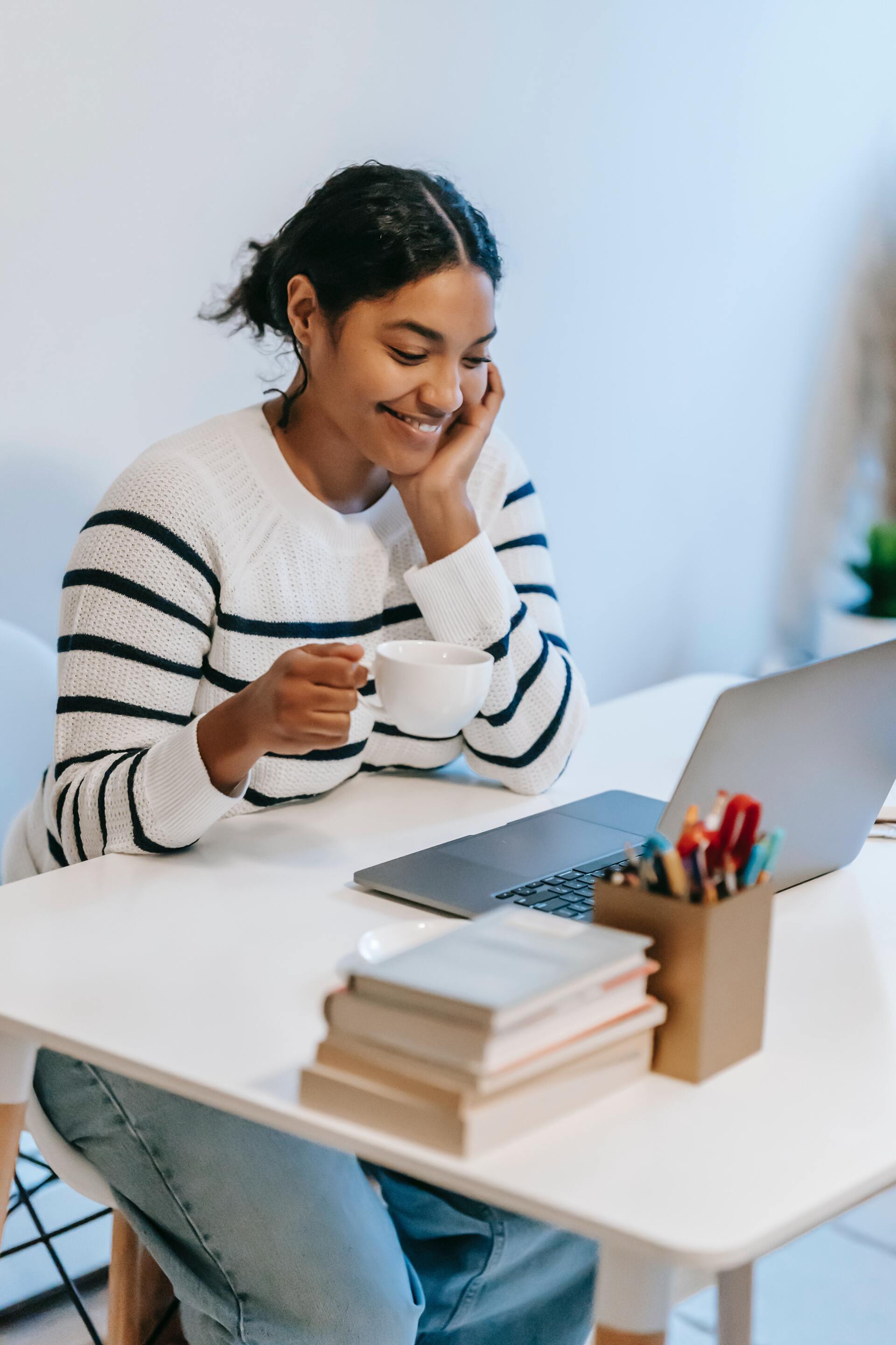 mujer feliz trabajando en computadora con taza de café