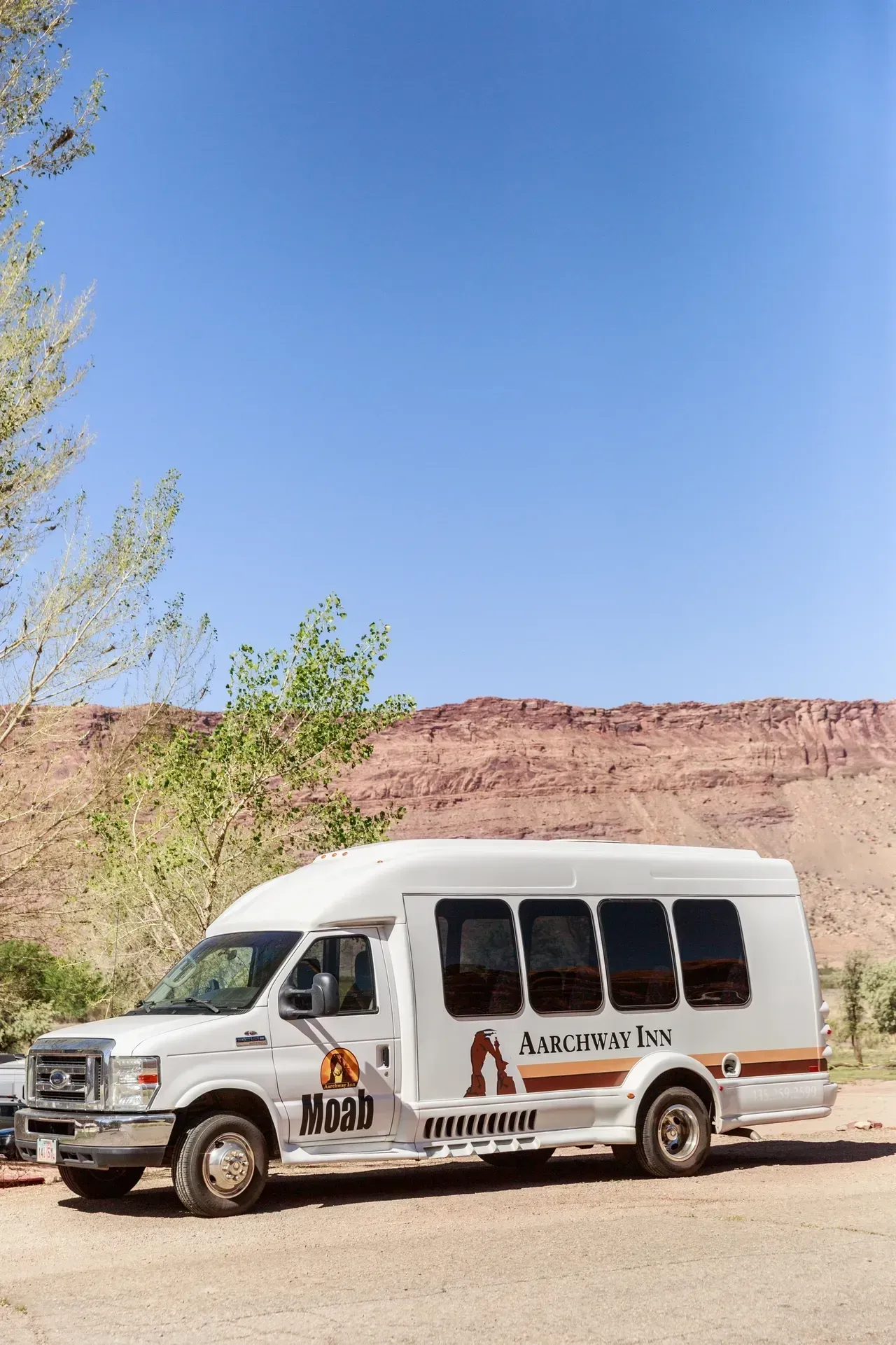 A white van is parked in a parking lot in front of a mountain.