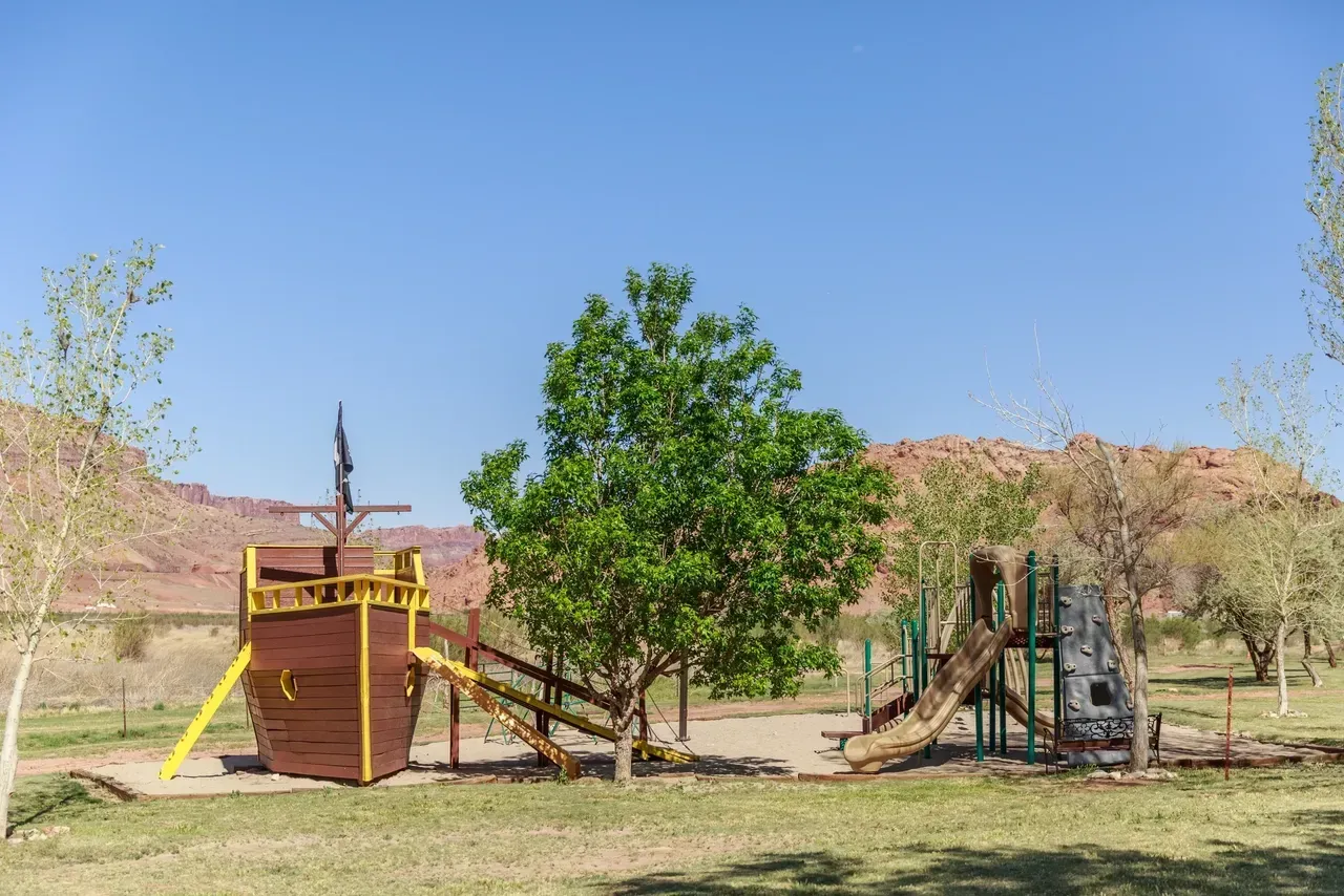 A playground in the shape of a pirate ship in a park.