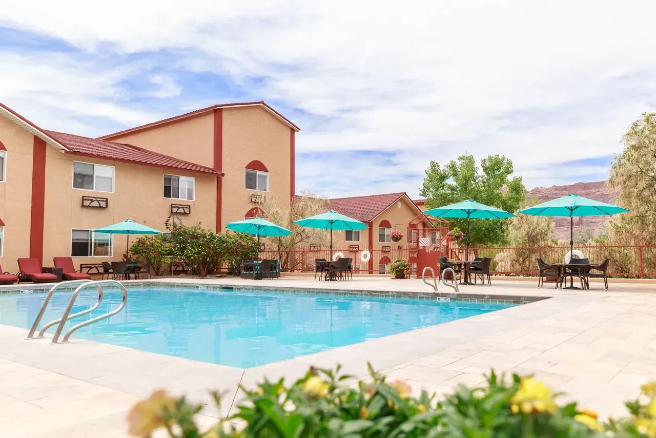 There is a large swimming pool in front of a hotel.