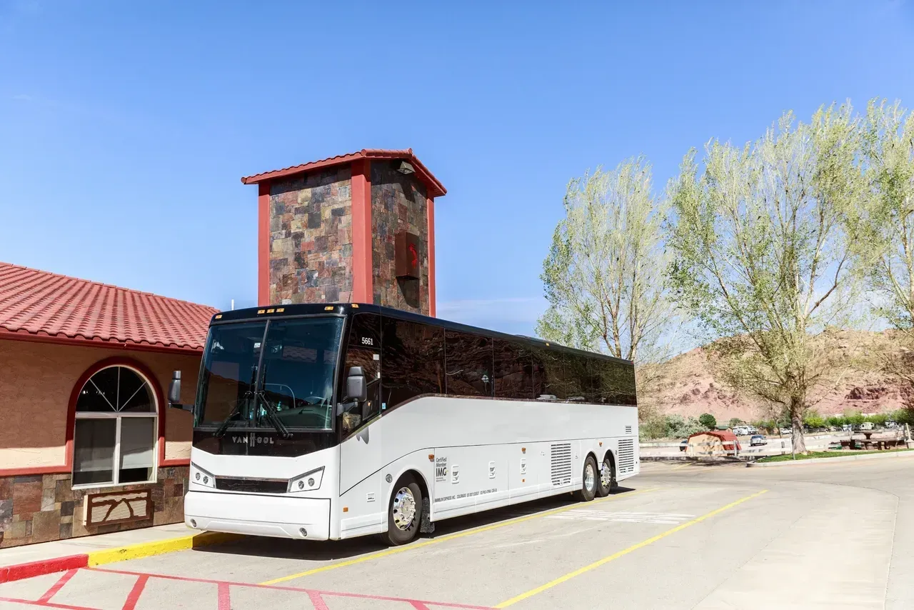 A large white bus is parked in front of a building.