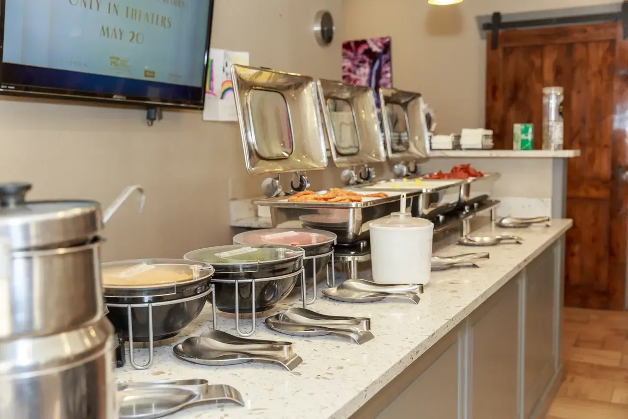 A buffet line in a restaurant with a tv on the wall.