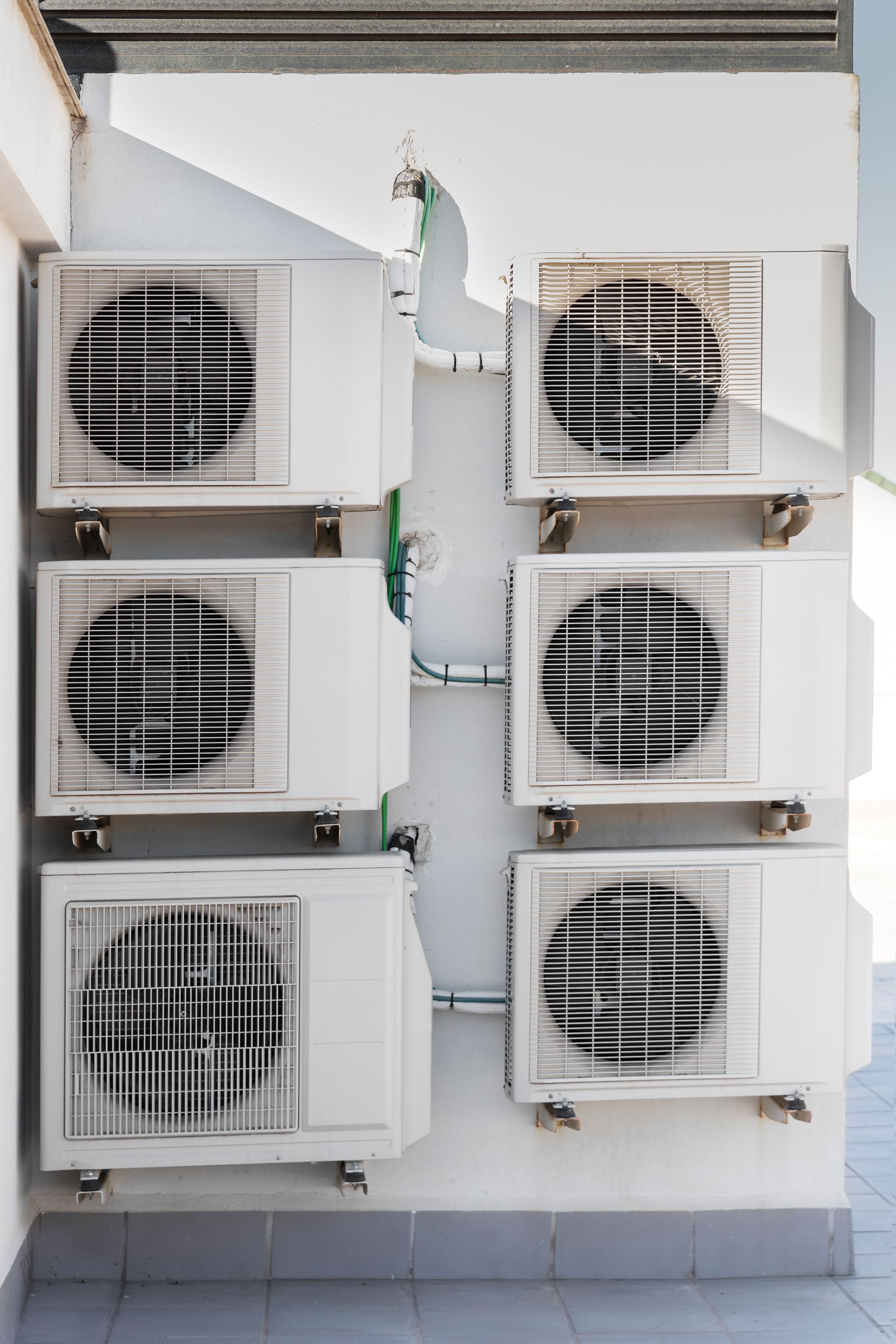 A row of air conditioners stacked on top of each other on a wall.