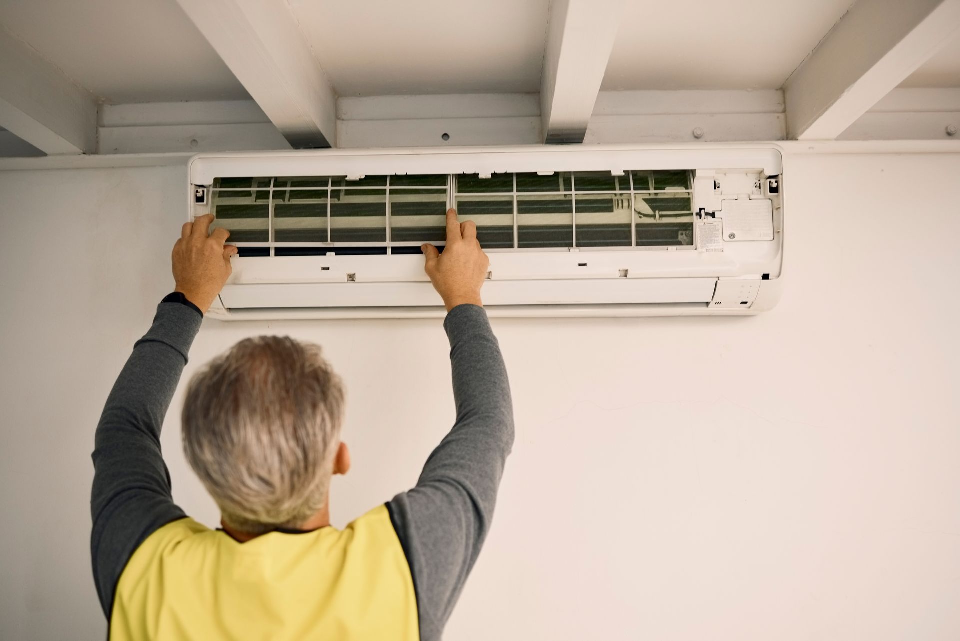 A man is cleaning the filter of an air conditioner.
