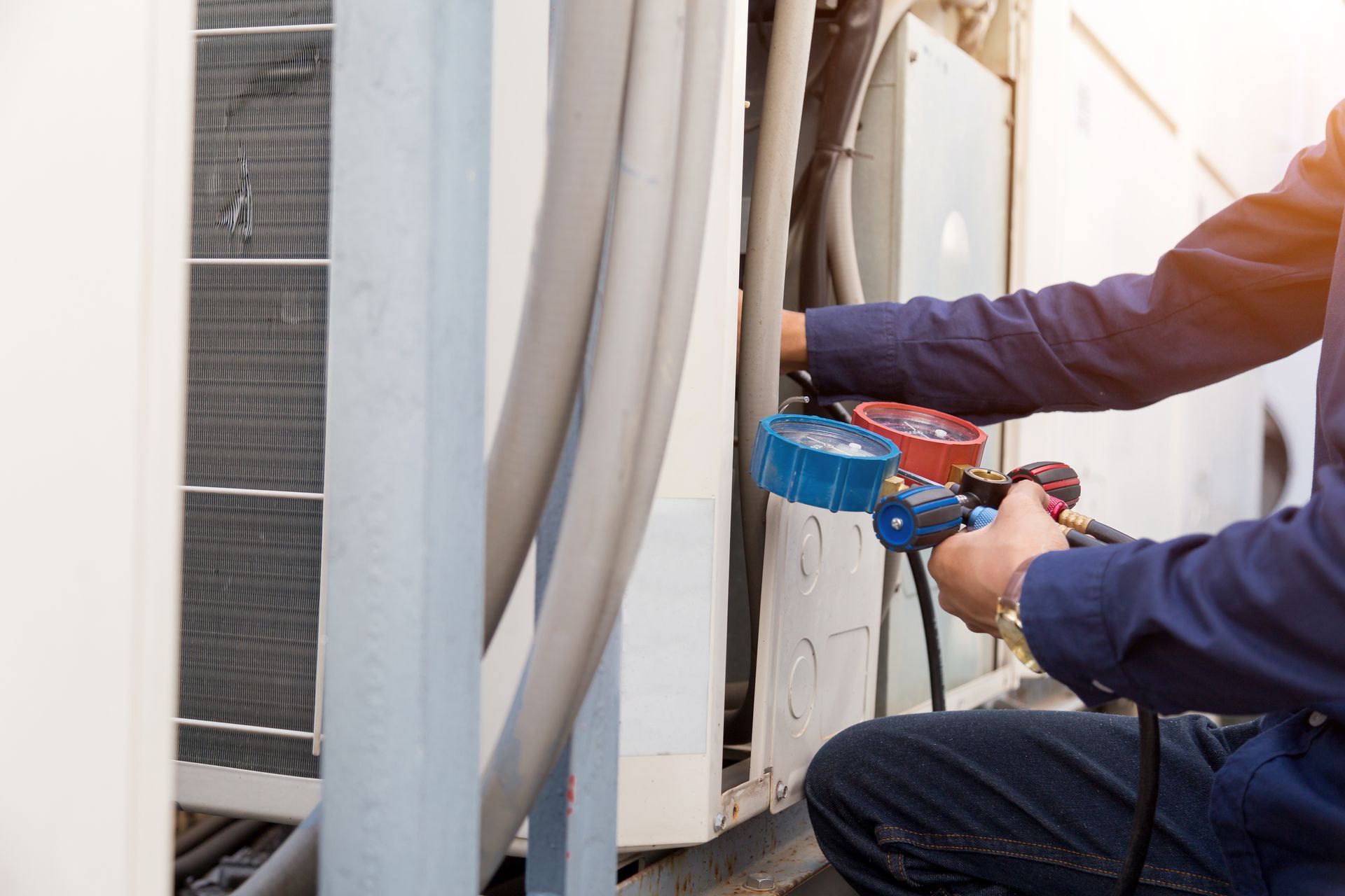 A man is kneeling down and working on an air conditioner.