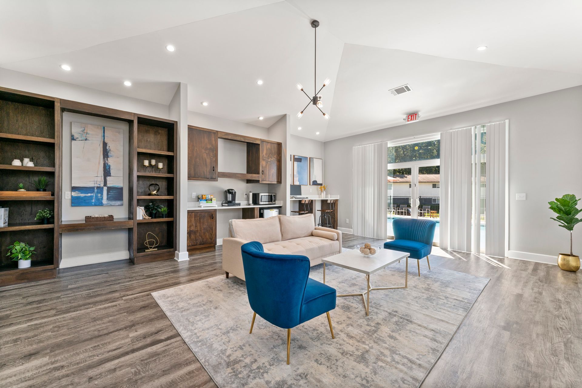 Bright modern living room with blue chairs, white sofa, wood floors, and large windows.
