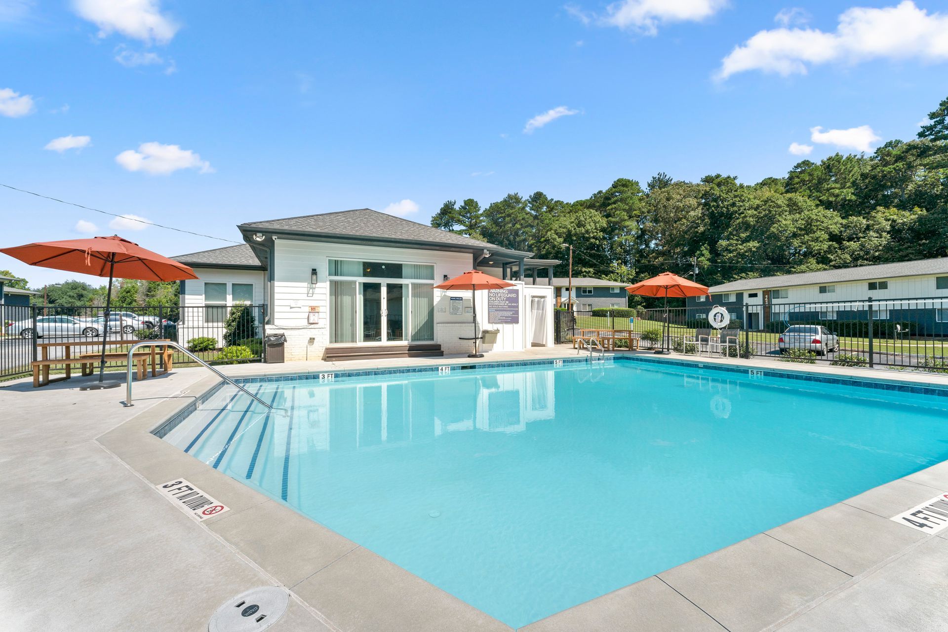 Outdoor swimming pool at a modern resort with lounge chairs, umbrellas, and a blue sky