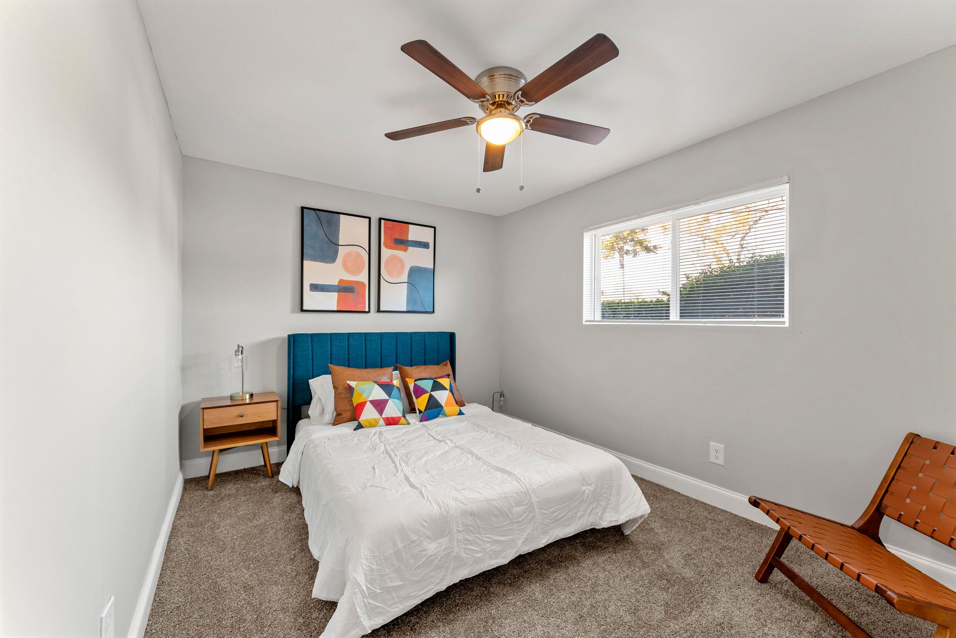 Small bedroom with a bed, wooden chair, ceiling fan, and window with blinds.