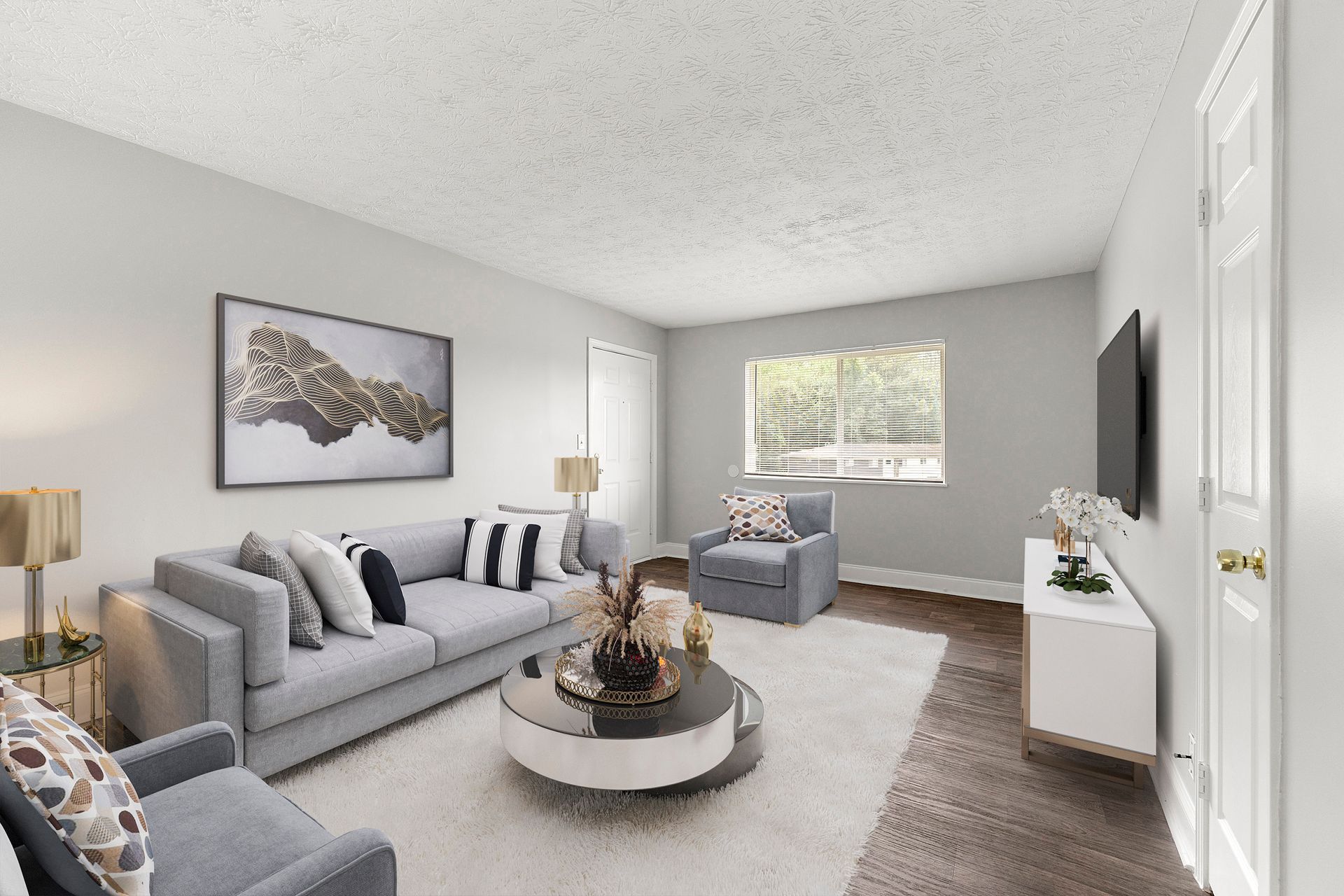 Bright living room with gray sofa, armchairs, rug, wall art, and a TV beside a window.