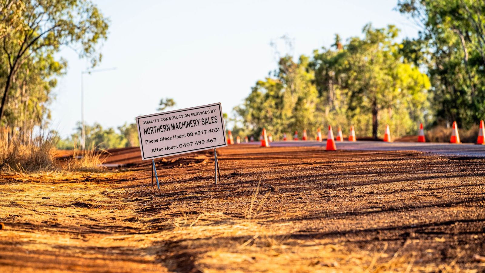 A sign is sitting on the side of a dirt road.