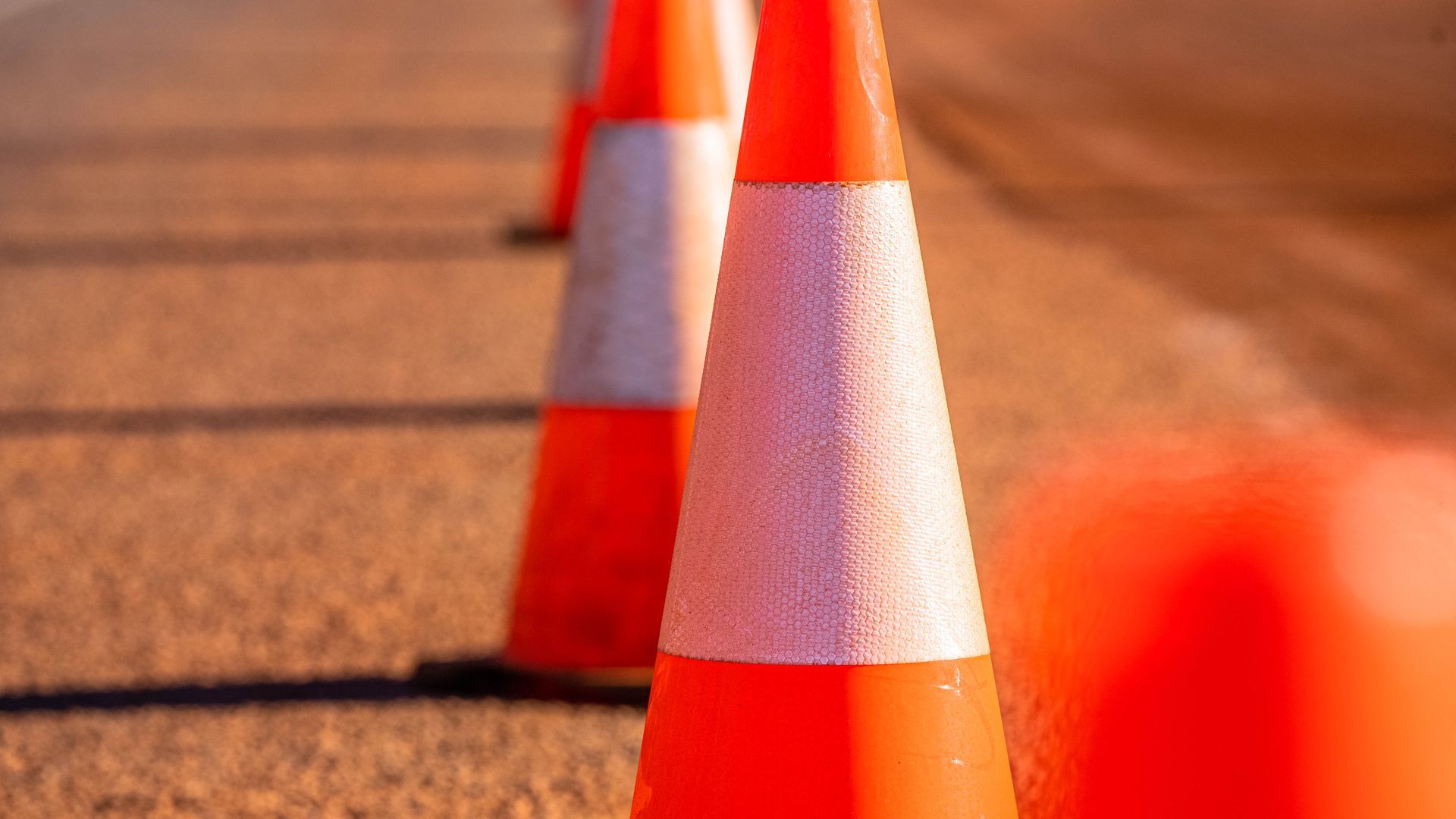 A row of orange and white traffic cones on the side of a road.