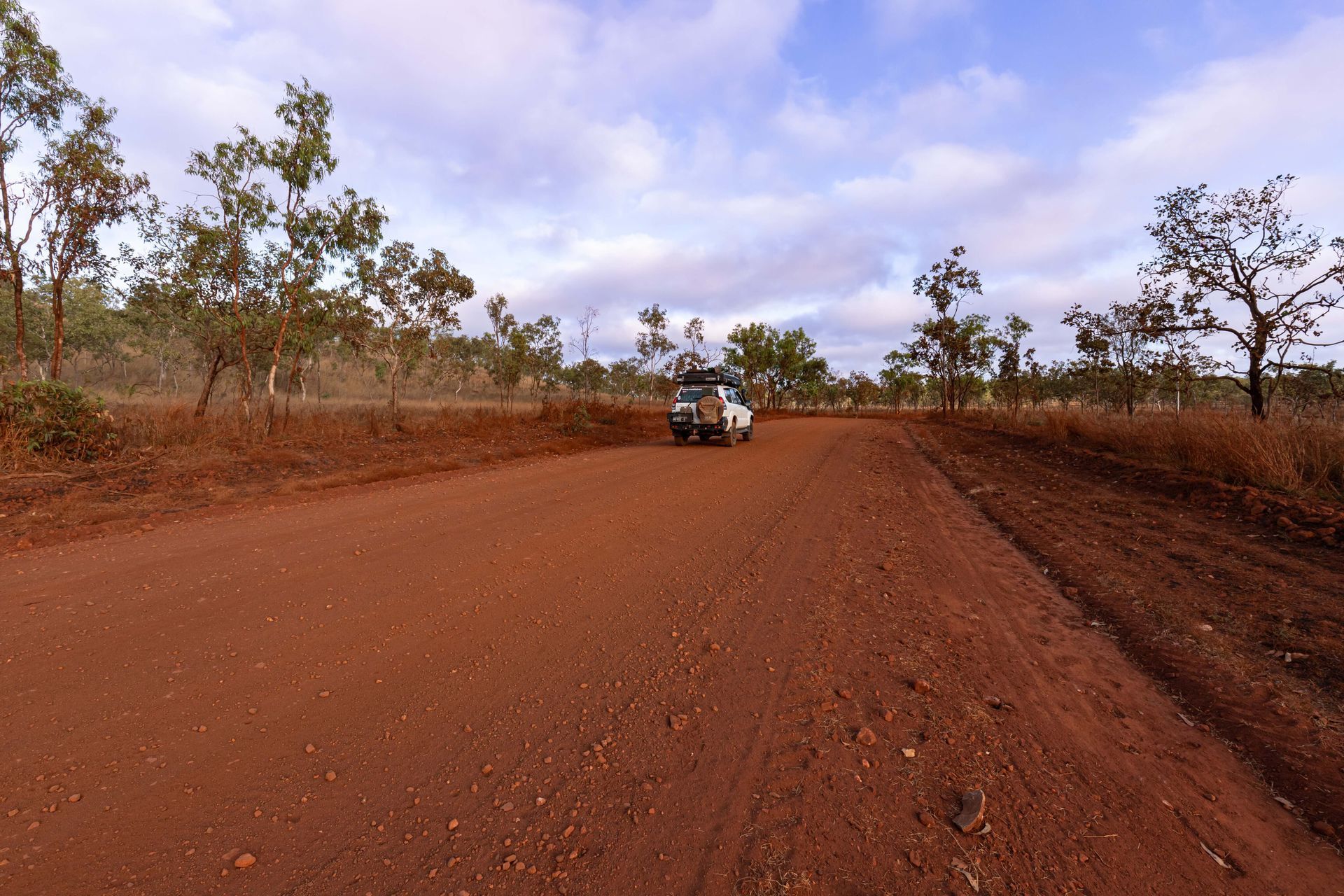 A white truck is driving down a dirt road