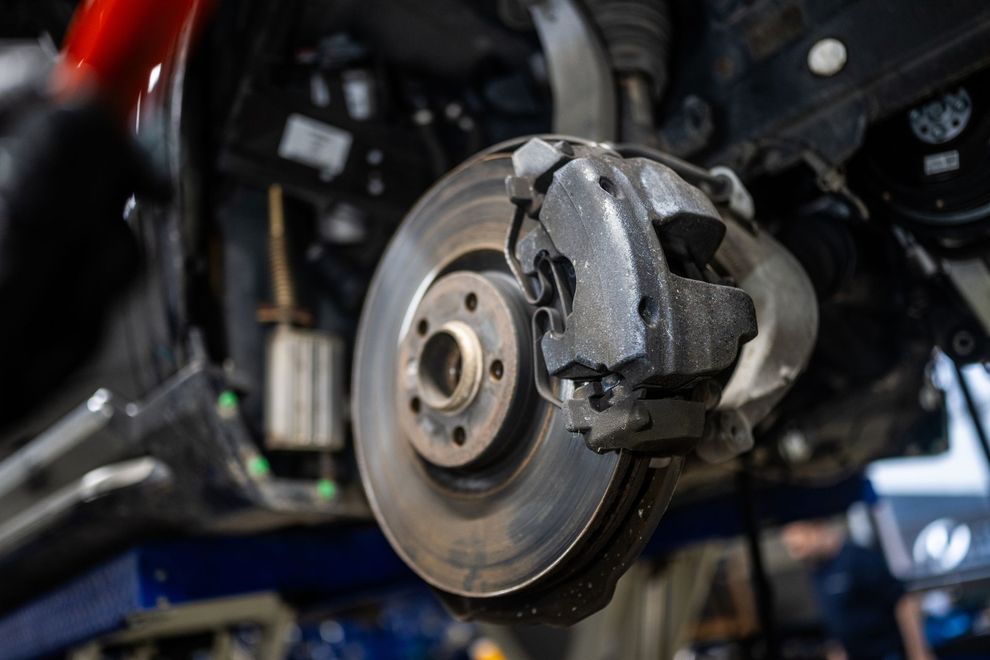 Disco freno e pinza dell'auto da vicino, probabilmente sottoposti a ispezione o riparazione in officina.
