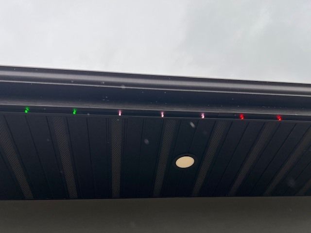 Dark gutter with evenly spaced green and red lights, against a cloudy sky.