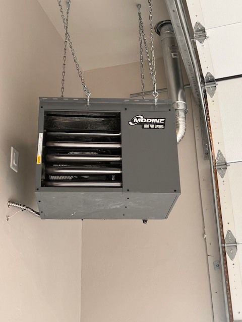 Ceiling-mounted Modine garage heater hanging by chains, with an exhaust vent near the garage door.