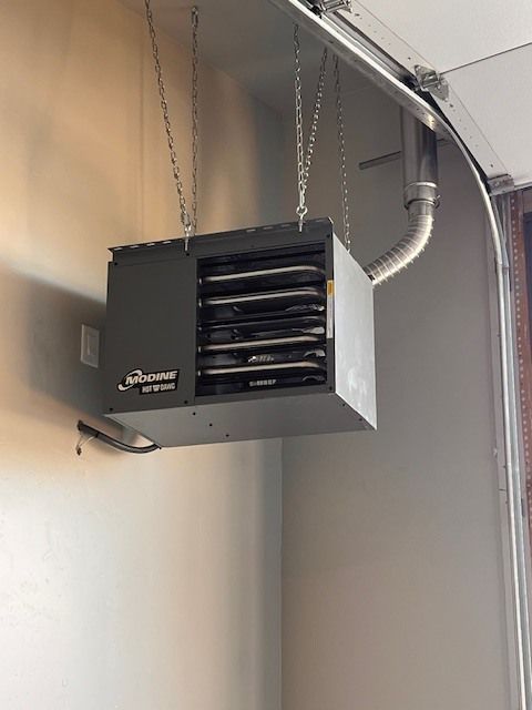Gray ceiling-mounted garage heater suspended by chains, near an open garage door.