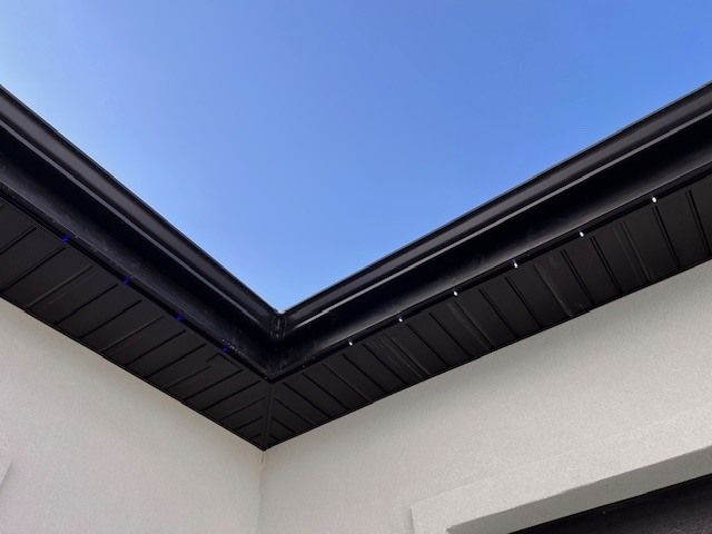 Black gutter and soffit on white building against a blue sky.
