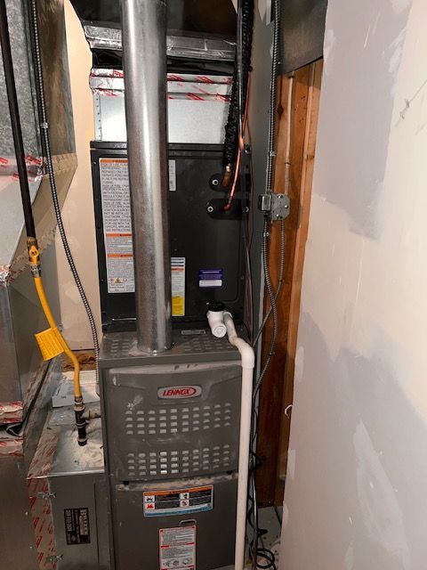 A Lennox furnace in a utility room with metal ductwork, gas line, and white piping.