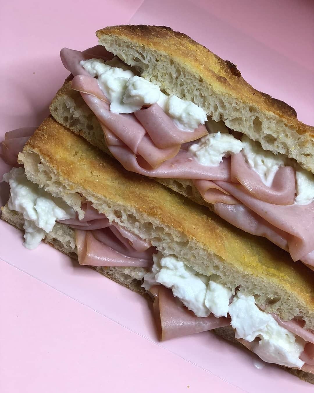 Close-up of a sandwich with ham and white cheese on a pink background