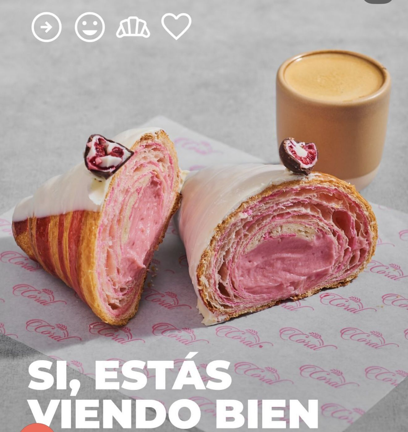 Pastelito relleno de rosa con glaseado blanco, cubierto con una baya, junto a un café pequeño. «Sí, estás viendo bien».