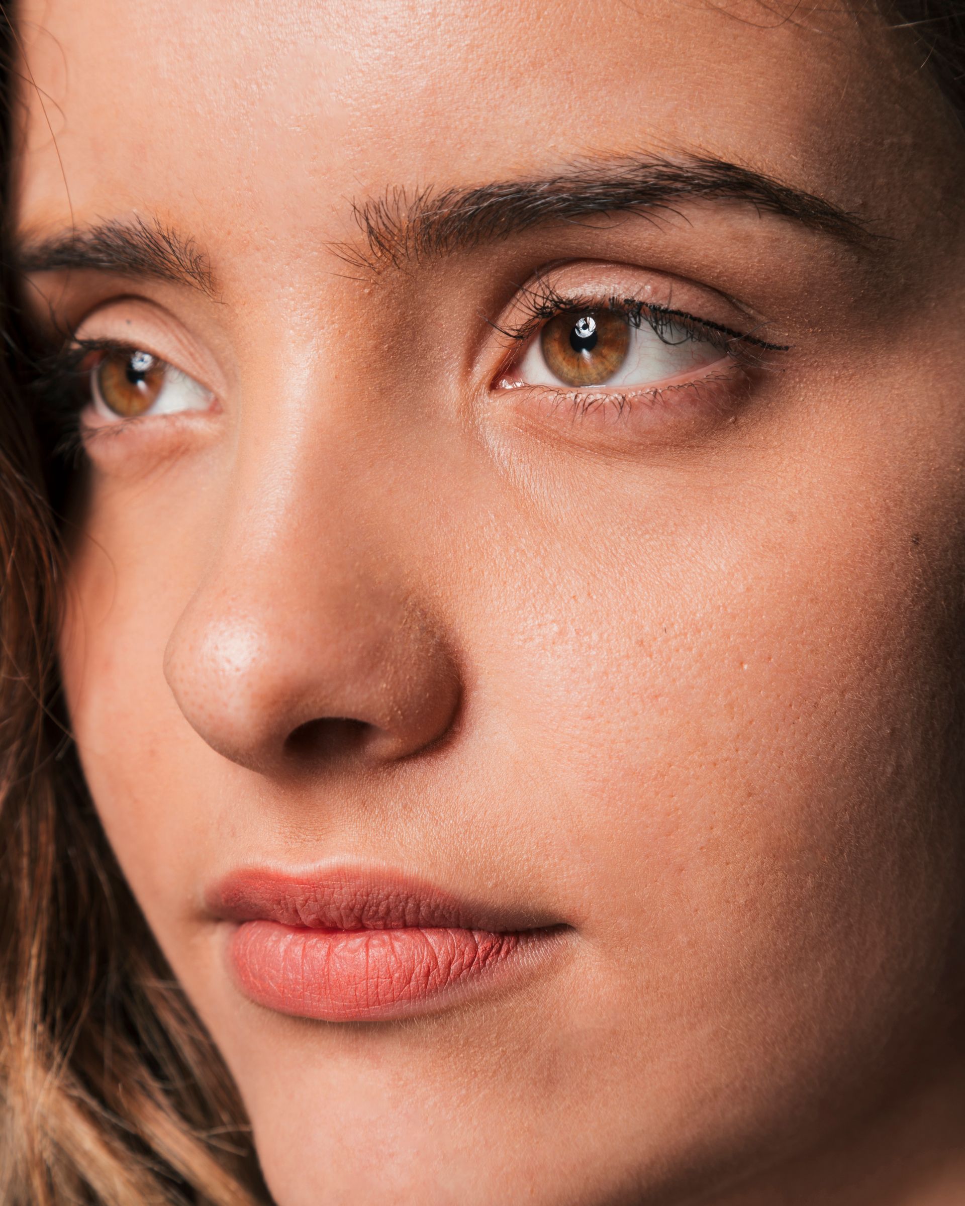 A close up of a woman 's face with brown eyes and red lips.