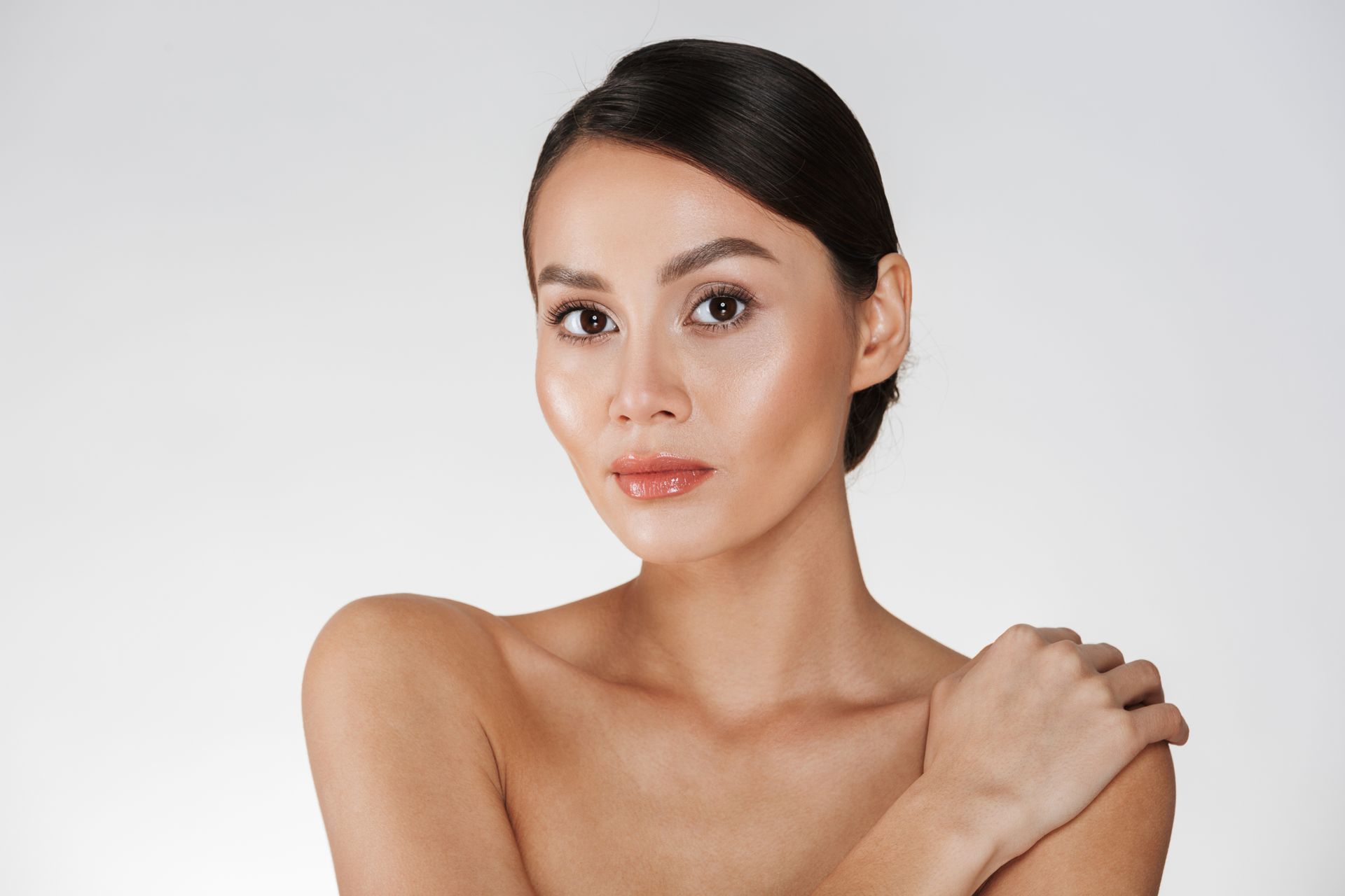A woman without a shirt is holding her shoulder and looking at the camera.