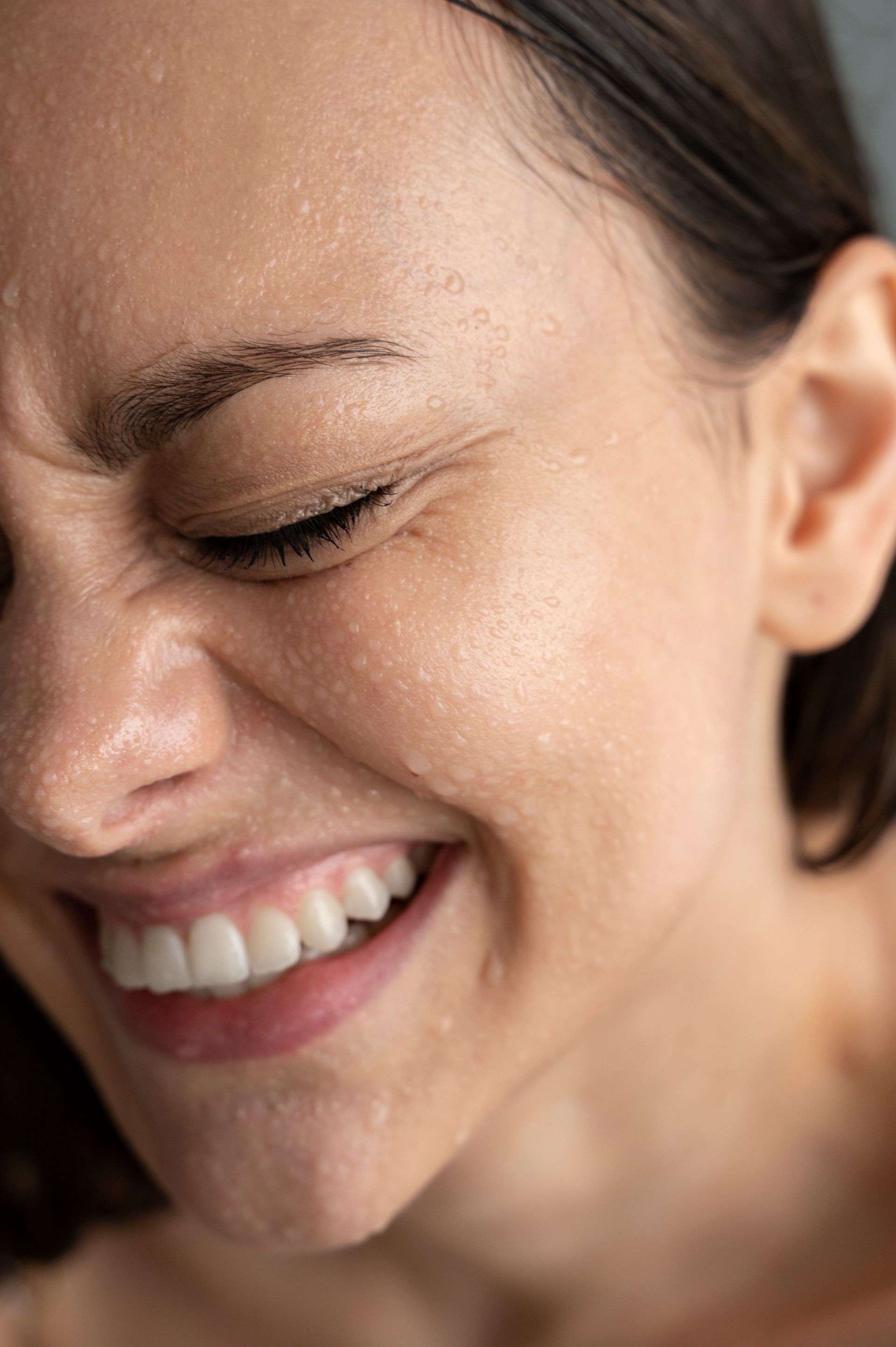 A close up of a woman 's face smiling with her eyes closed.