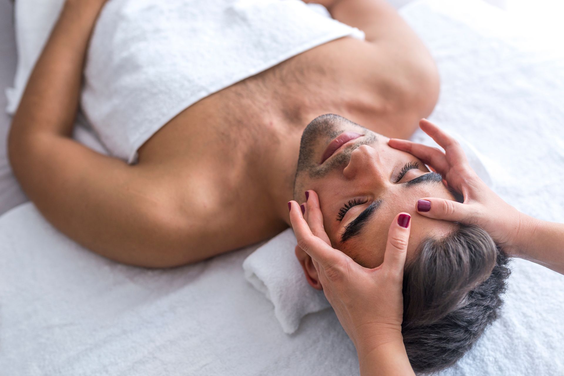 A man is getting a facial massage at a spa.