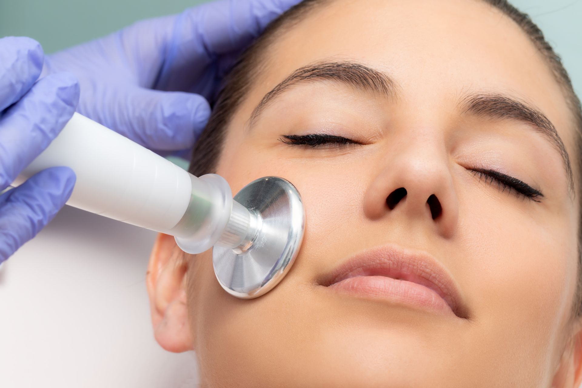 A woman is getting a facial treatment with a stethoscope on her face.