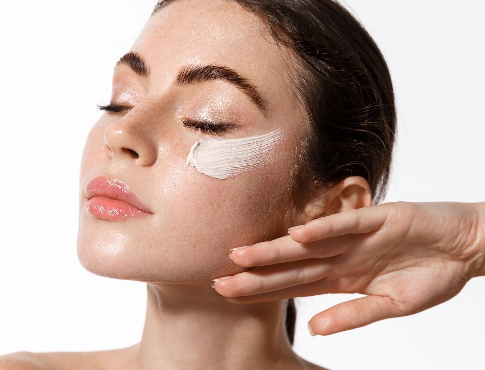 A woman is applying a cream to her face.