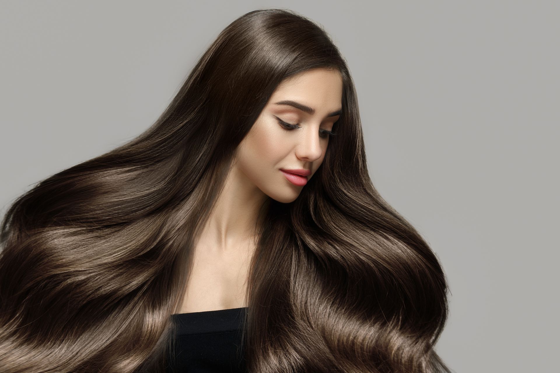 A woman with very long hair is wearing a black top.