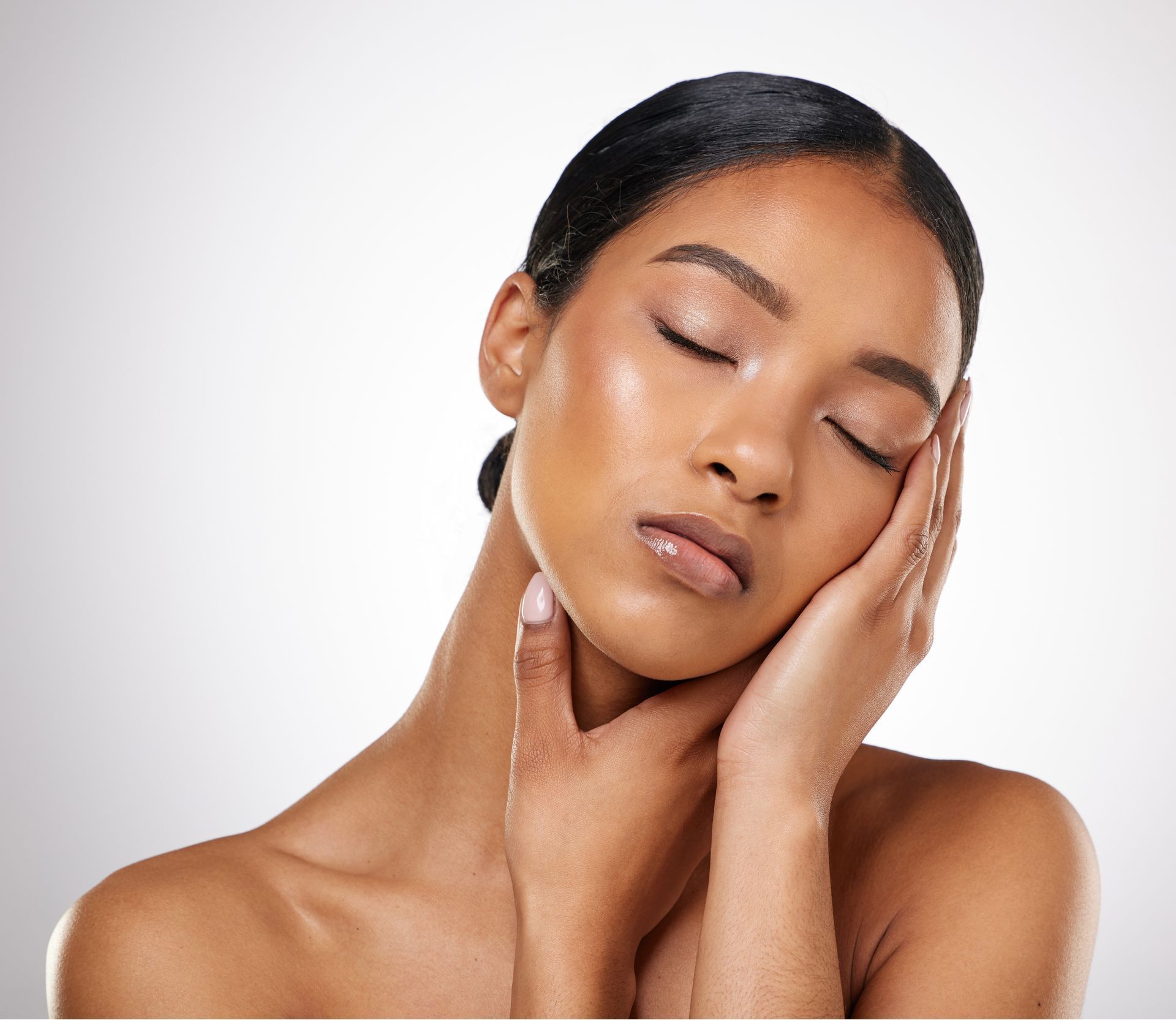 A woman with her eyes closed is touching her face with her hand.