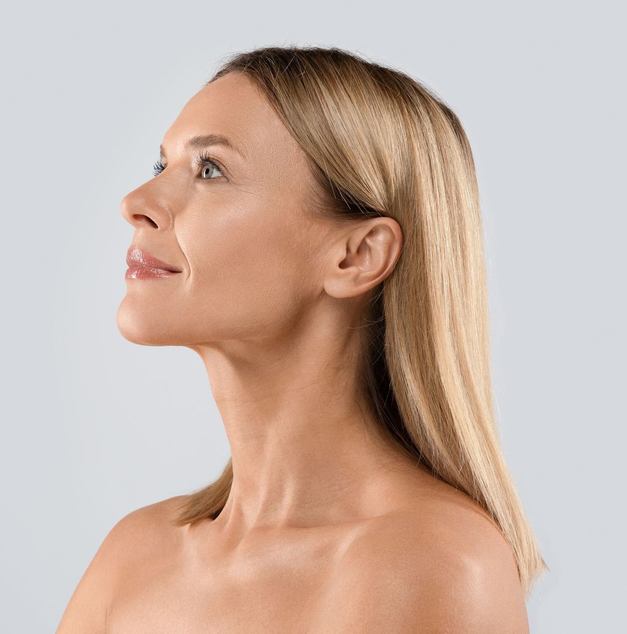 A woman without a shirt is looking up at the sky.